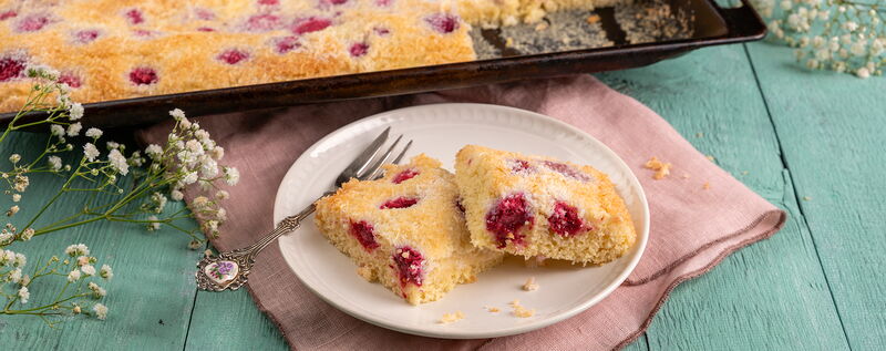 Saftiger Kokoskuchen vom Blech mit versunkenen Himbeeren.