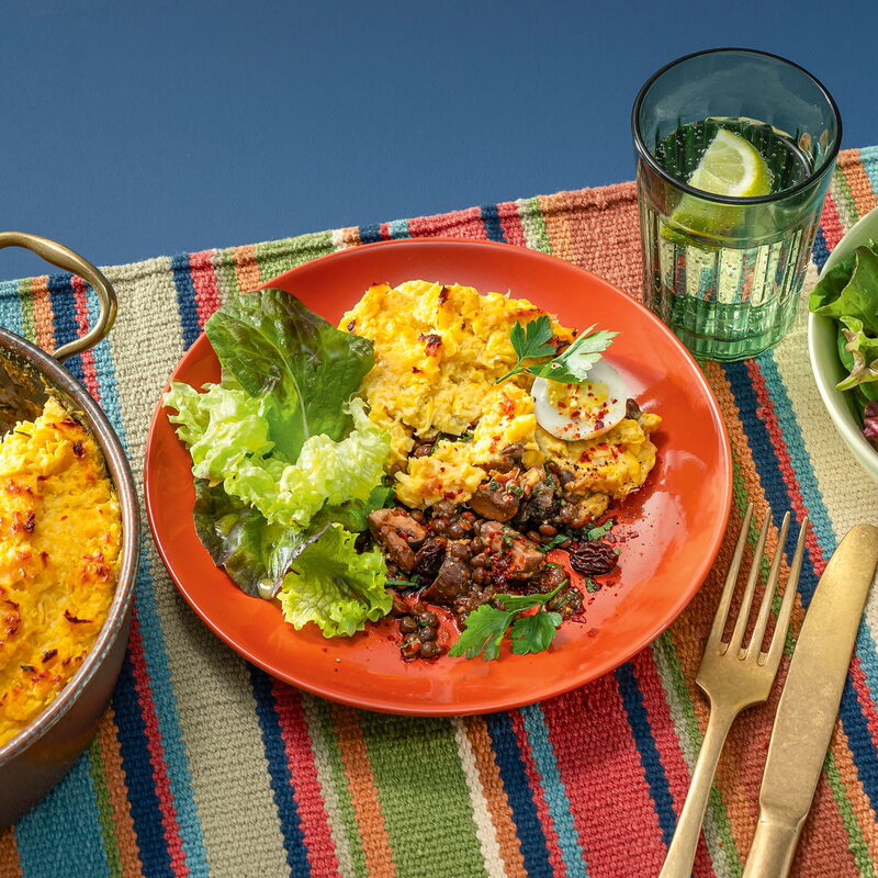 Maisauflauf mit Linsen-Pilz-Füllung und grünem Salat, angerichtet auf einem Teller.