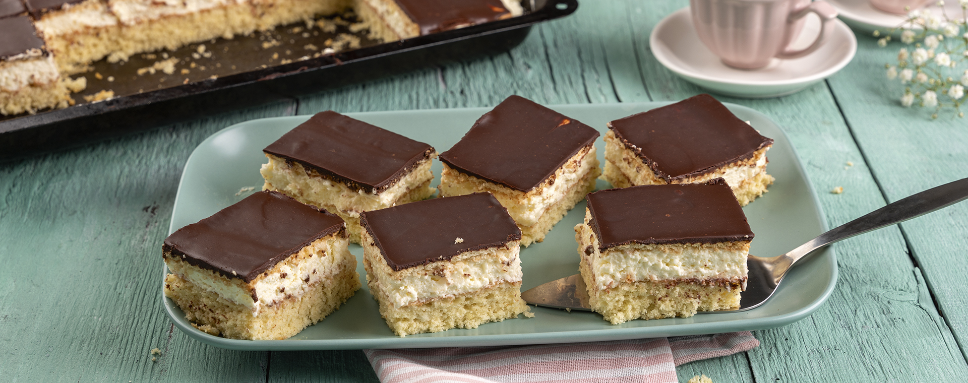 Butterkeksschnitten vom Blech mit Zitronencreme und Schokoladenglasur, angerichtet auf einer Servierplatte.