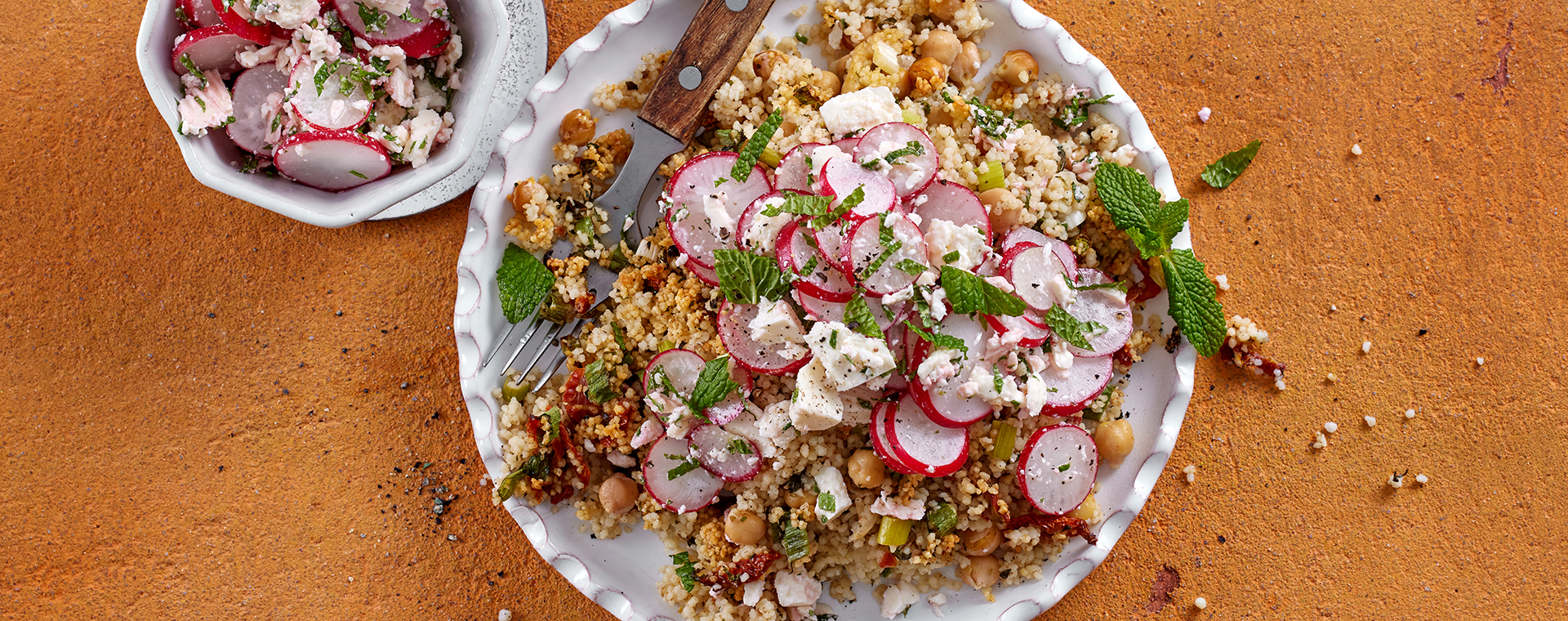 Schneller Couscousauflauf mit Kichererbsen und Radieschen-Feta-Topping, garniert mit frischer Minze.