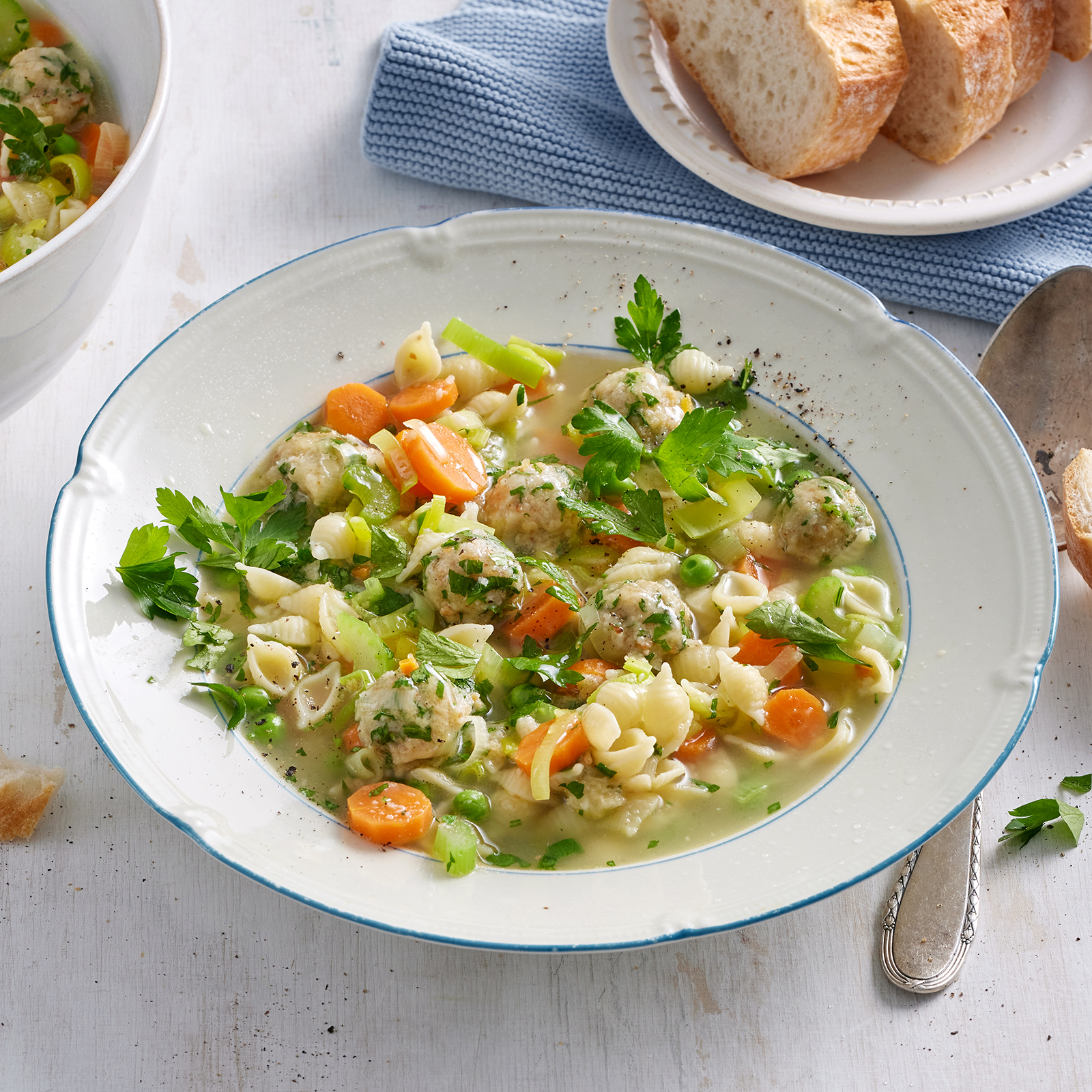 Gemüsesuppe mit Butter-Käse-Klößchen und Muschelnudeln in einem tiefen Teller.