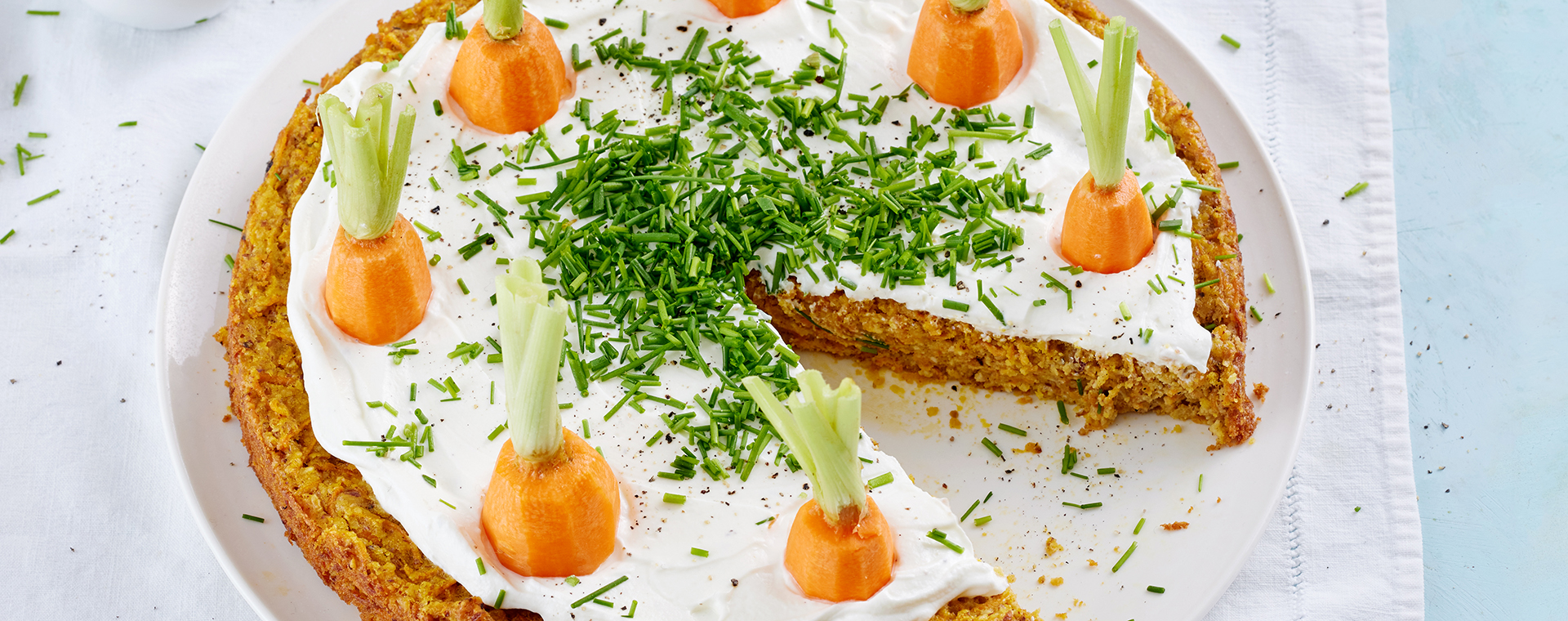 Herzhafter Möhrenkuchen mit Schnittlauchquark-Frosting auf einer Servierplatte.