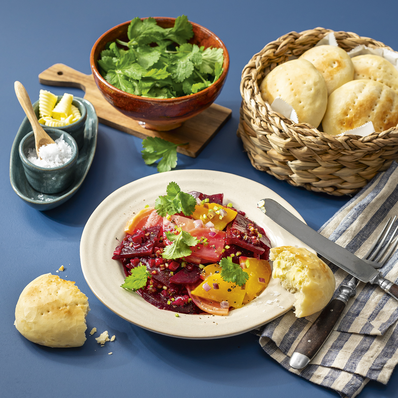 Rote-Bete-Salat mit frischem Koriander in einem tiefen Teller, dazu Weizenbrötchen mit Butter und Salz.