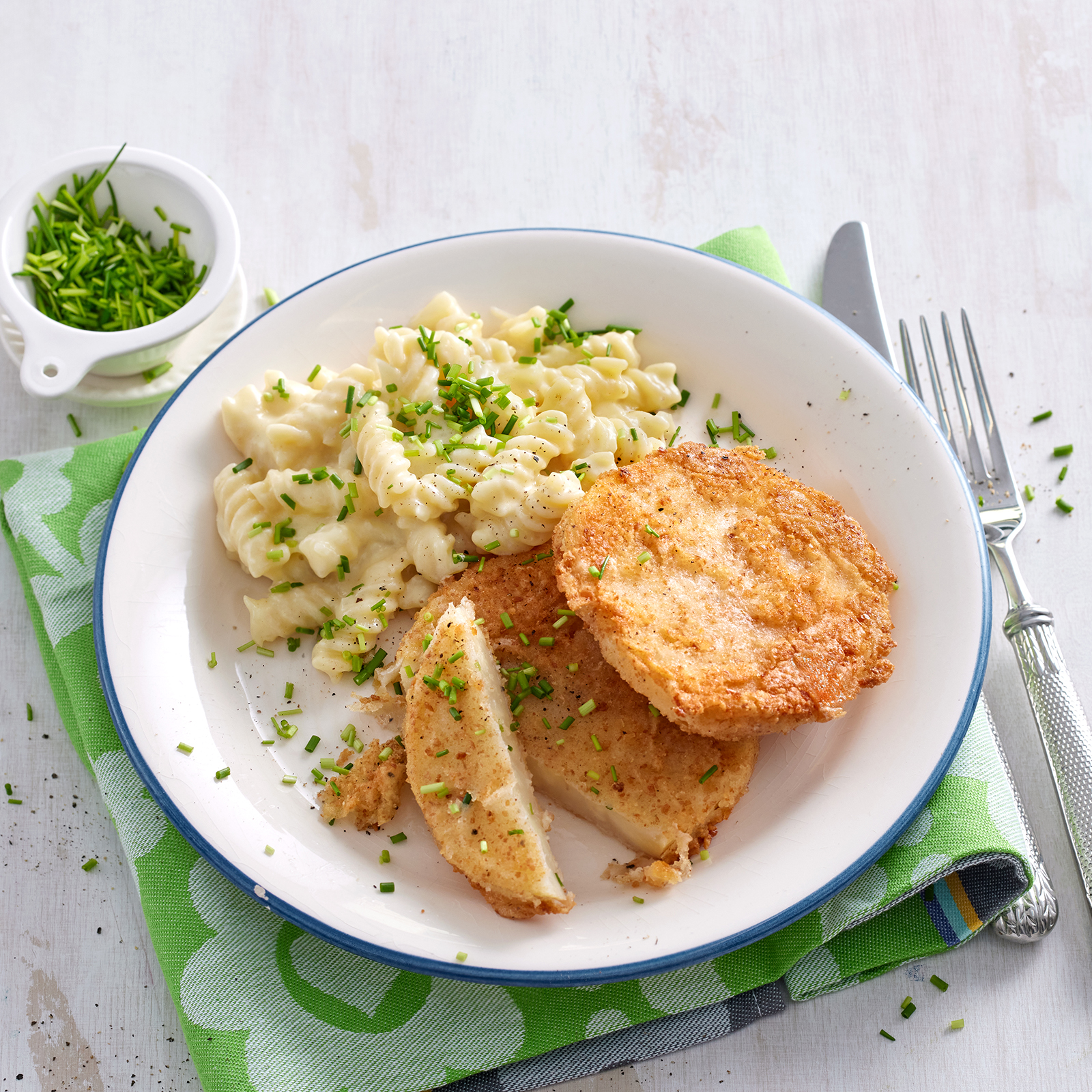 Sellerieschnitzel mit Käsenudeln und frischem Schnittlauch, angerichtet auf einem Teller.