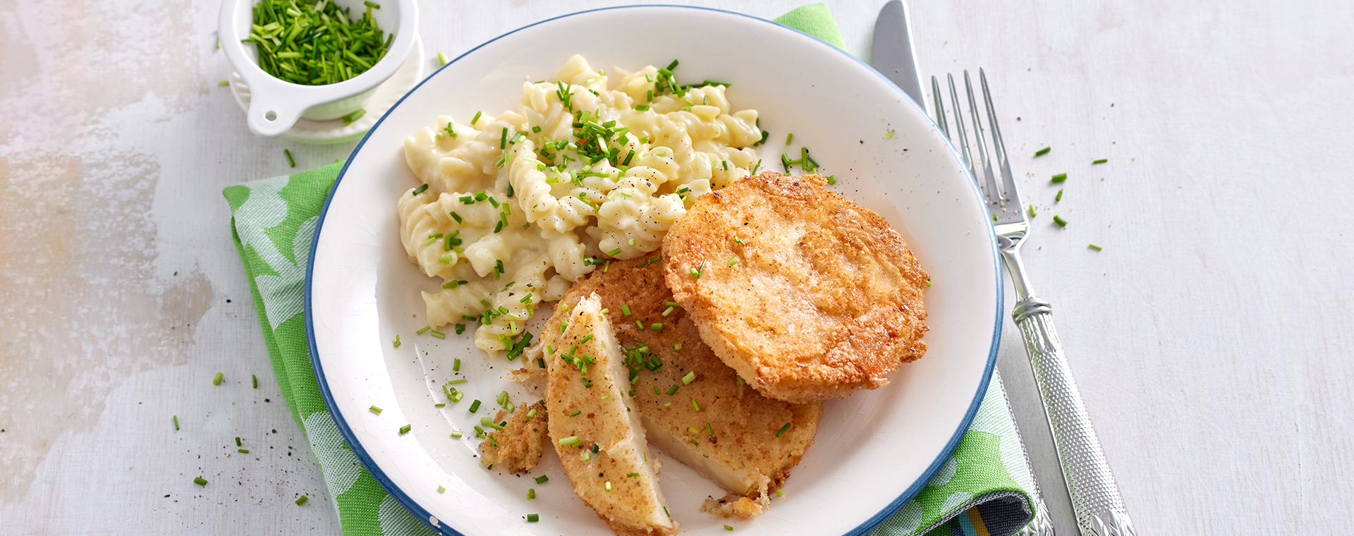 Sellerieschnitzel mit Käsenudeln und frischem Schnittlauch, angerichtet auf einem Teller.